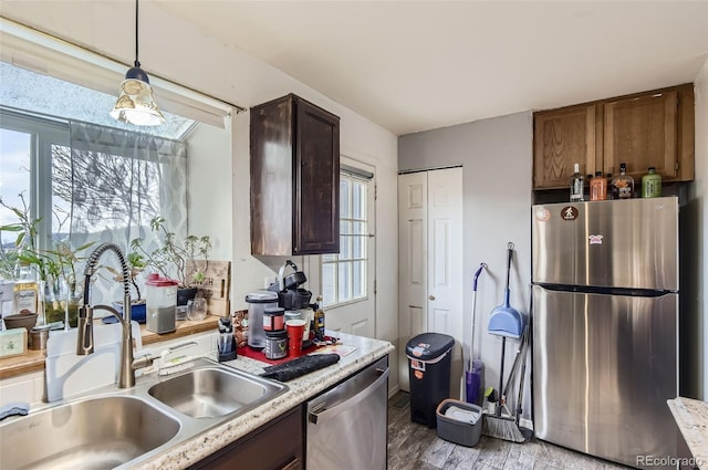 kitchen with hanging light fixtures, light wood-type flooring, a sink, light countertops, and stainless steel appliances