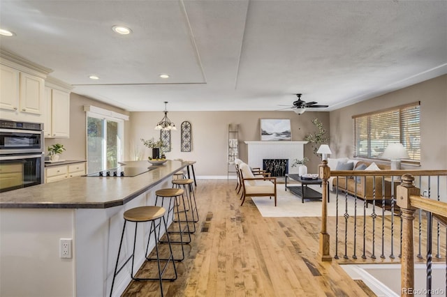 kitchen featuring a breakfast bar, black electric cooktop, a fireplace, and plenty of natural light