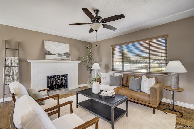 living room with ceiling fan, baseboards, wood finished floors, and a fireplace