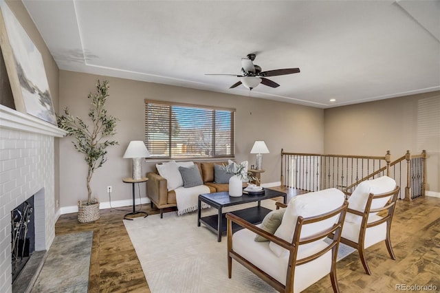 living area with a ceiling fan, wood finished floors, baseboards, recessed lighting, and a fireplace