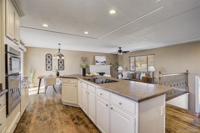 kitchen featuring a kitchen island, black electric stovetop, recessed lighting, a fireplace, and wood finished floors