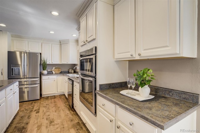 kitchen featuring light wood finished floors, dark countertops, recessed lighting, white cabinets, and stainless steel appliances