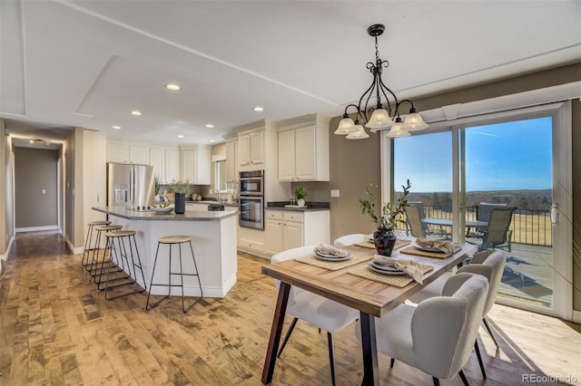 dining space with a chandelier, recessed lighting, light wood-type flooring, and baseboards