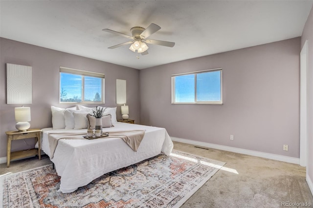 carpeted bedroom with visible vents, a ceiling fan, and baseboards