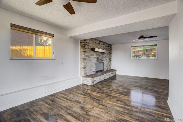 unfurnished living room featuring a fireplace, wood finished floors, baseboards, and a textured ceiling