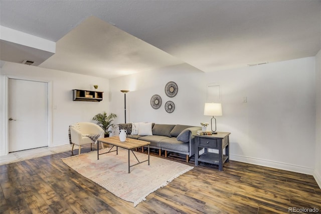 living area featuring visible vents, baseboards, and wood finished floors