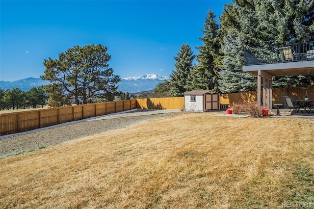 view of yard with an outdoor structure, a storage unit, a fenced backyard, and a mountain view