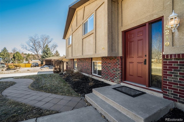 doorway to property featuring brick siding and stucco siding