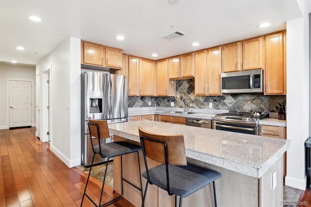 kitchen with appliances with stainless steel finishes, a kitchen breakfast bar, and a center island