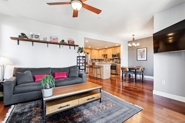 living room featuring ceiling fan with notable chandelier and light wood-type flooring