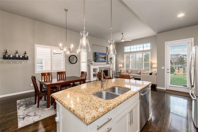 kitchen with sink, white cabinetry, stainless steel appliances, a center island with sink, and decorative light fixtures