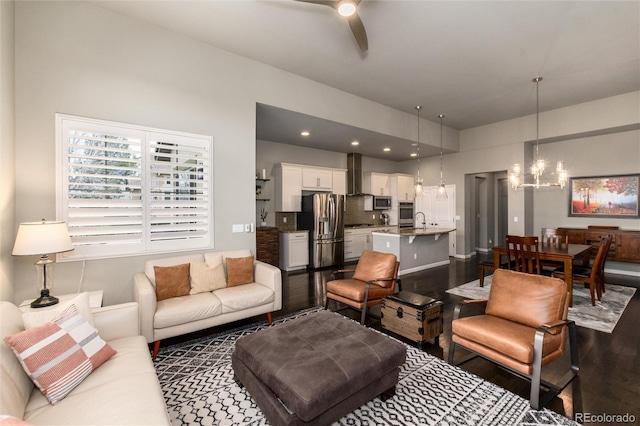 living room with dark hardwood / wood-style flooring and ceiling fan with notable chandelier