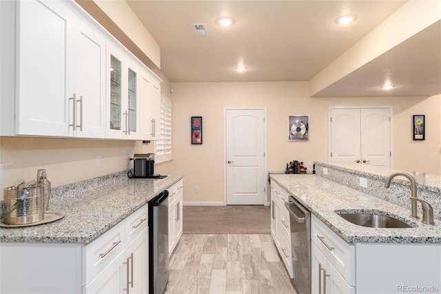 kitchen with white cabinetry, sink, stainless steel dishwasher, and light stone counters