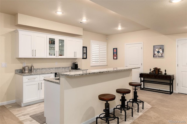 kitchen featuring light stone countertops, a center island, white cabinets, and a kitchen bar