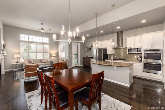 dining area with sink, ceiling fan with notable chandelier, and dark hardwood / wood-style floors