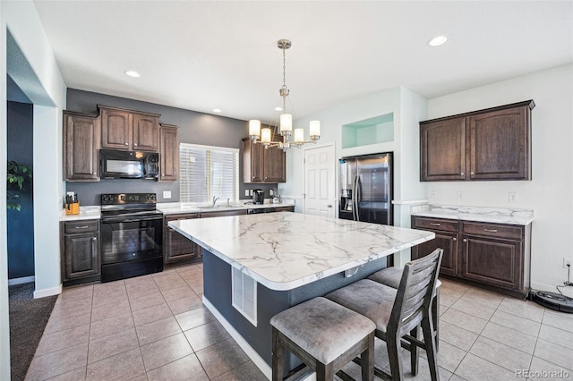 kitchen with dark brown cabinetry, sink, a center island, hanging light fixtures, and black appliances