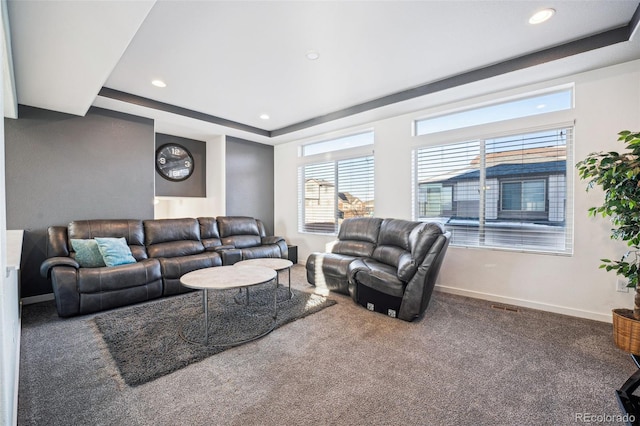 living room with a tray ceiling and carpet floors