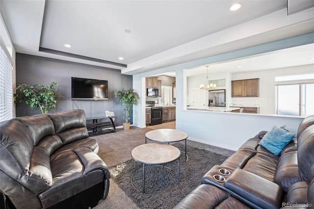 carpeted living room with a raised ceiling and a chandelier