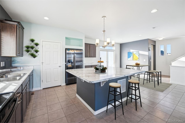 kitchen featuring a kitchen island, decorative light fixtures, sink, dark brown cabinetry, and stainless steel appliances