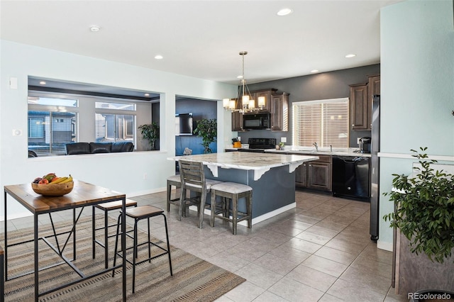 kitchen with a kitchen breakfast bar, open floor plan, a center island, dark brown cabinets, and black appliances