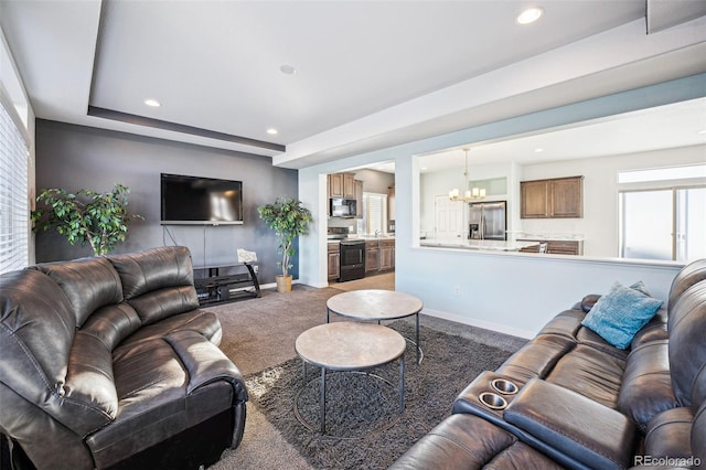 carpeted living area featuring recessed lighting, a raised ceiling, a notable chandelier, and baseboards