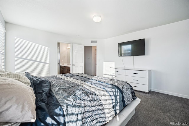 bedroom featuring visible vents, dark carpet, ensuite bath, and baseboards