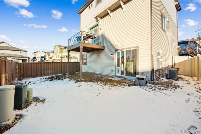 snow covered rear of property featuring a residential view, cooling unit, a fenced backyard, and a balcony
