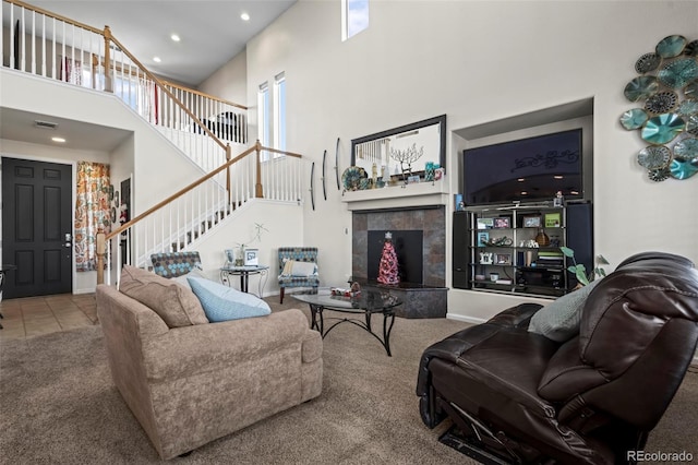 living room with a tiled fireplace, carpet, and a high ceiling