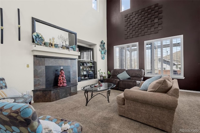 carpeted living room featuring a towering ceiling and a fireplace