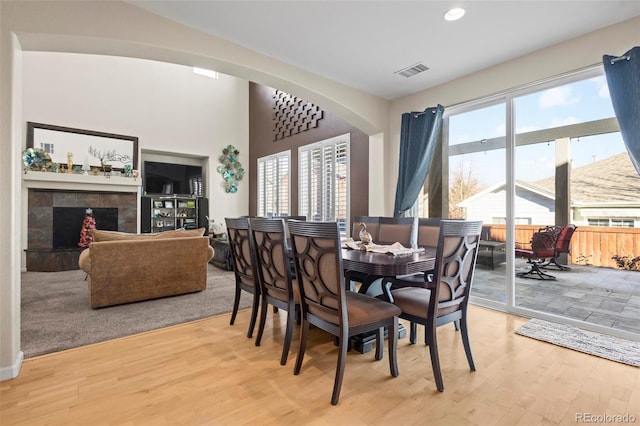 dining area with a fireplace, plenty of natural light, wood-type flooring, and built in shelves