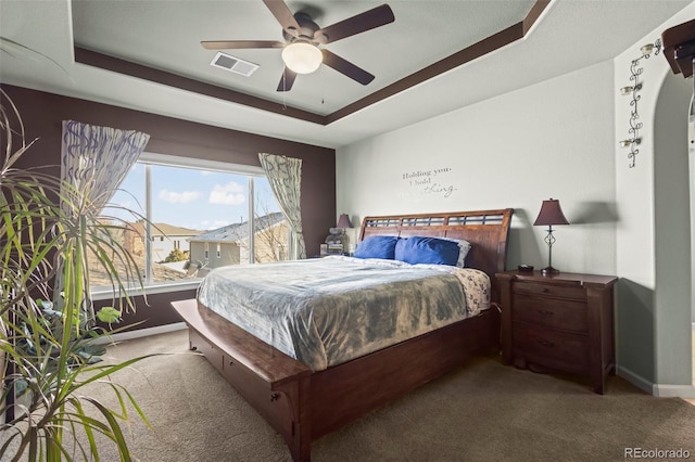 carpeted bedroom featuring ceiling fan and a tray ceiling