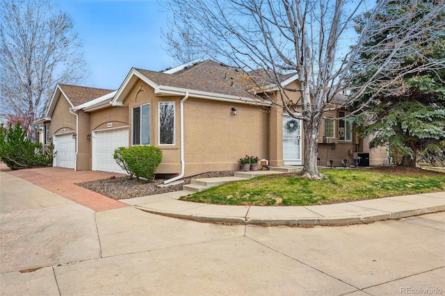 view of property exterior with stucco siding, a garage, a yard, concrete driveway, and roof with shingles