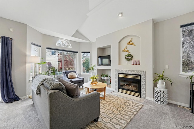 living room featuring a tile fireplace, carpet floors, baseboards, vaulted ceiling, and built in features