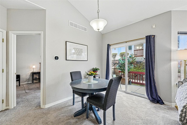 dining room with light carpet, lofted ceiling, and baseboards