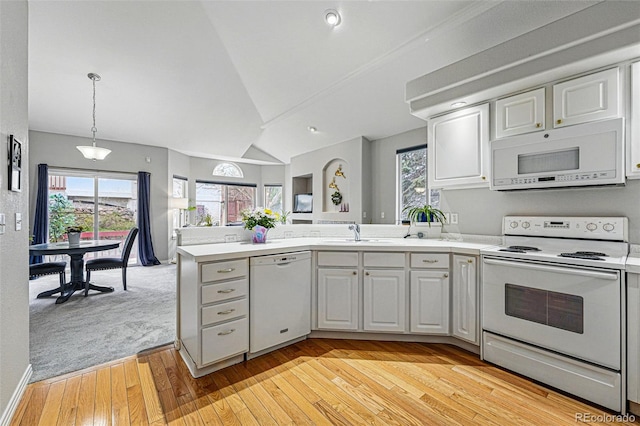 kitchen with white appliances, a peninsula, a sink, light countertops, and vaulted ceiling