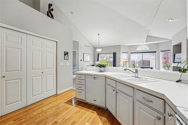 kitchen featuring dishwasher, a sink, light wood-style floors, open floor plan, and light countertops