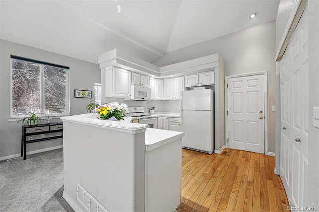 kitchen featuring white appliances, white cabinetry, a peninsula, vaulted ceiling, and light countertops