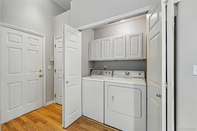 washroom with cabinet space, washer and clothes dryer, and light wood-type flooring