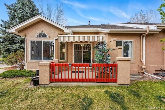 back of property featuring stucco siding, a lawn, and a deck
