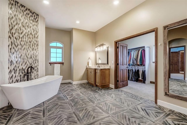 bathroom featuring tile walls, vanity, and a bath