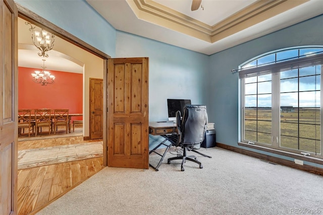 home office with a tray ceiling, wood-type flooring, and ceiling fan with notable chandelier