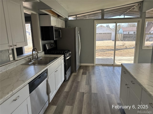 kitchen featuring dark hardwood / wood-style floors, white cabinetry, sink, light stone counters, and stainless steel appliances