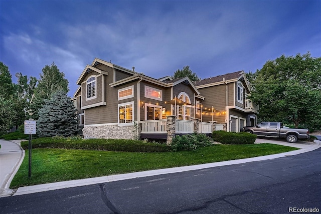 view of front of home with a garage, stone siding, driveway, and a front yard