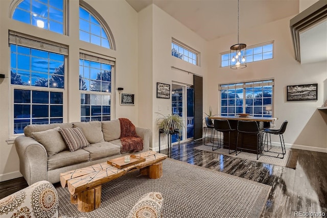 living area with a towering ceiling, baseboards, and wood finished floors