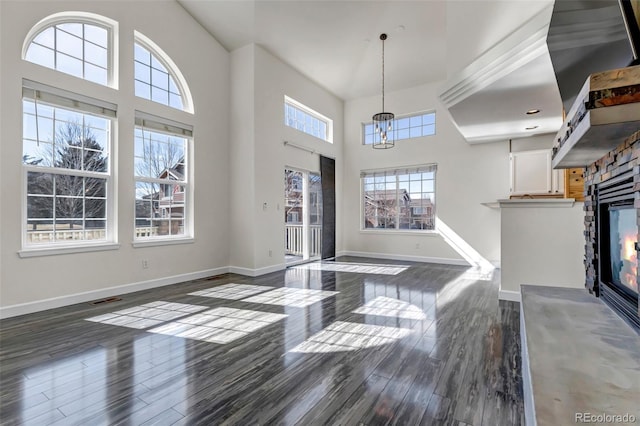 interior space featuring visible vents, dark wood finished floors, a stone fireplace, and a towering ceiling