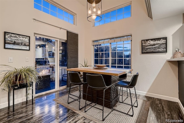 dining space with a high ceiling, baseboards, and wood finished floors