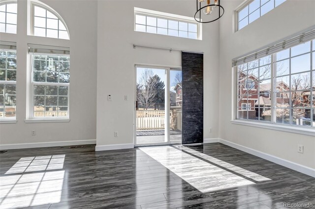 entrance foyer with dark wood finished floors, a towering ceiling, and baseboards