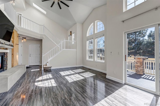 entryway featuring a fireplace, wood finished floors, high vaulted ceiling, baseboards, and stairs