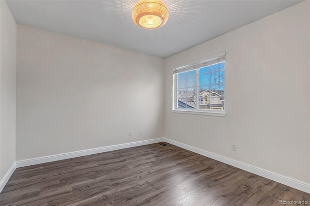 spare room featuring baseboards and wood finished floors