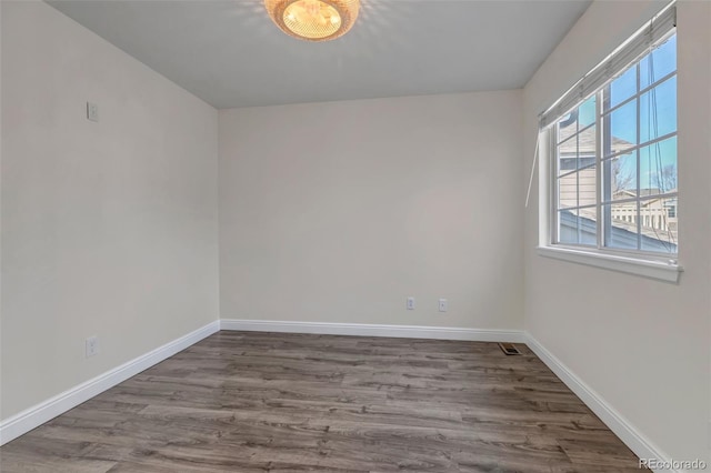 unfurnished room with wood finished floors, visible vents, and baseboards